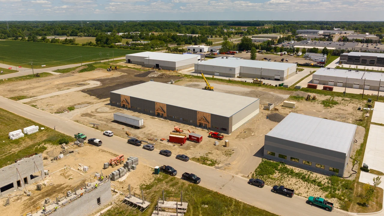 After: completed industrial building visualized within the real aerial site photograph